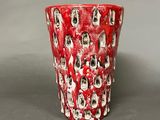 a red vase with skulls on it on a table