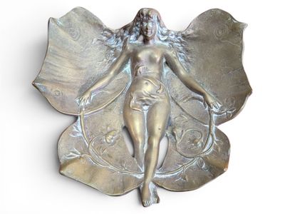 une sculpture métallique représentant une femme ailée posée sur une feuille