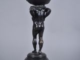 an image of a statue of a boy holding a globe on his head