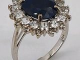 une image représentant une bague ornée d'une grosse pierre bleue entourée de petits diamants blancs