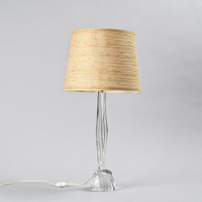 a clear glass lamp with a beige shade on top of it