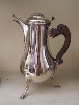 a silver coffee pot sitting on a shelf next to a vase