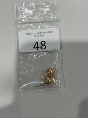 un sachet de perles dorées posé sur une table blanche