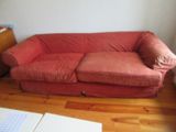 un canapé rouge posé sur un parquet en bois massif