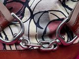 a purse with a chain hanging from it on a pink surface