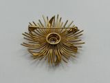 a close up of a gold brooch on a white surface