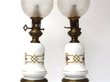 pair of white and gold lamps with glass globes on them