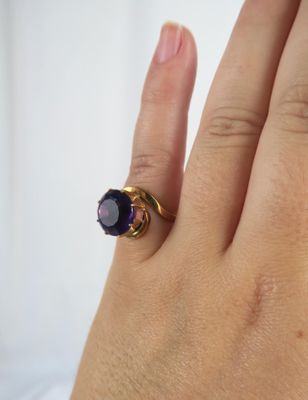 someone is holding a ring with a purple stone on it