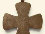 an old bronze cross pendant on a white background