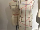 three mannequins are lined up on a stand in front of a wall