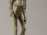 statue en bronze représentant un garçon portant un chapeau et une veste, posée sur une table en bois