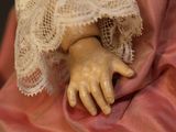 a close up of a doll with a pink dress and lace