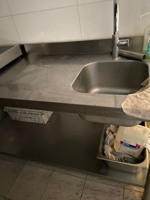 a sink in the corner of a kitchen with a towel on the counter