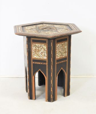 une table d'appoint dont le plateau présente un motif noir et or