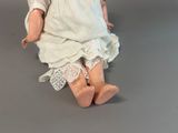 a doll that is sitting on the floor wearing a white dress