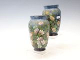 deux vases décorés de fleurs, posés sur un socle