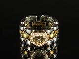 une image représentant un bracelet en or et en argent posé sur une surface noire