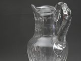 un pichet en verre transparent muni d'une anse, posé sur une table