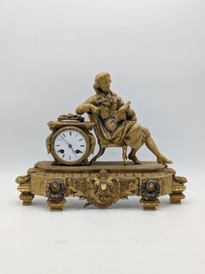 une statue d'un homme assis au sommet d'une horloge