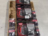 three boxes of black and red backpacks sitting on top of a pile of hay