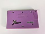 purple electronic device sitting on top of a white table next to a white wall