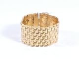 gros plan d'un bracelet en or sur une surface blanche