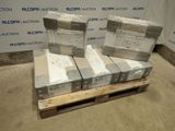 Plusieurs cartons sont empilés sur une palette devant un mur.