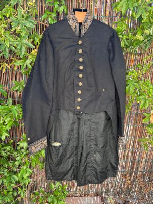 une veste noire accrochée à une clôture en bambou, près d'un buisson