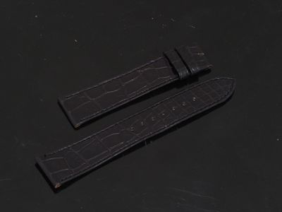 une paire de bracelets de montre en cuir d'alligator noir posés sur un fond noir