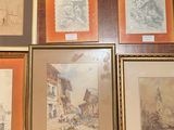 many framed pictures on the wall of a room
