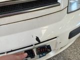 a close up of a person ' s hand pointing at the front of a car