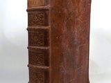 an old brown book sitting on top of a table next to a white wall