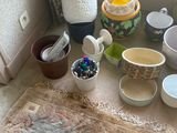 de nombreux bols et tasses posés par terre près d'une fenêtre