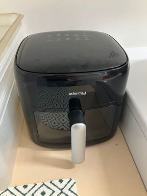 une friteuse à air chaud noire posée sur un plan de travail dans une cuisine