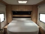 a bed in the middle of a small room with windows