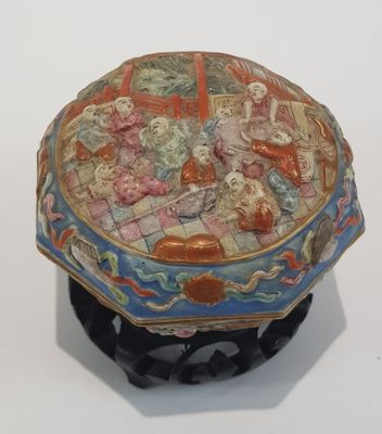 une petite boîte décorative posée sur un socle, sur une surface blanche