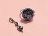 an image of a ring and a pendant on a pink surface