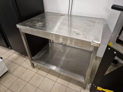 a stainless steel table in a kitchen with a black refrigerator