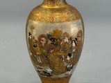 a gold vase with a painting on it on a table