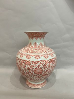 a red and white vase sitting on a table