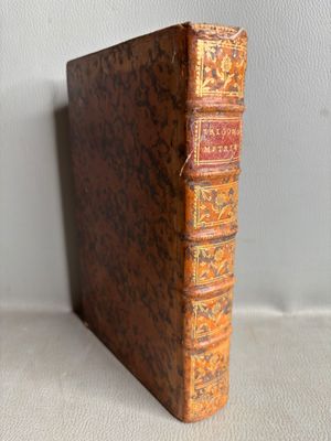 un vieux livre posé sur une table à côté d'un mur blanc