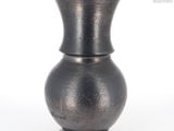 un vase noir posé sur une surface blanche