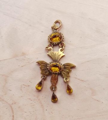 une photo d'un pendentif doré posé sur une table en bois