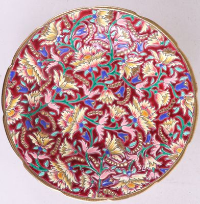 a close up of a red and gold plate with flowers on it