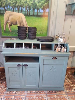 un tableau représentant une vache accroché au mur derrière une armoire bleue