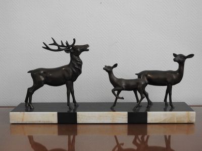 trois statues de cerfs posées sur un socle en marbre