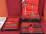 two trays of silverware on a red table