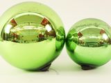 two shiny green christmas balls sitting next to each other