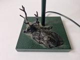 a statue of a deer laying down on a green surface
