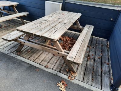 two wooden picnic tables on the deck of a house